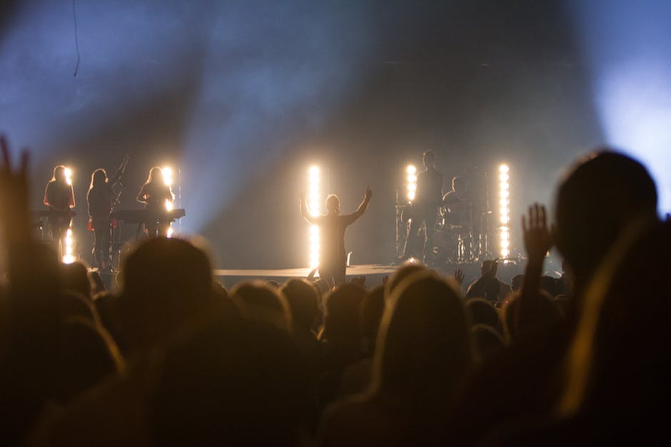 Vibrant live music concert with silhouetted band and cheering crowd under bright stage lights