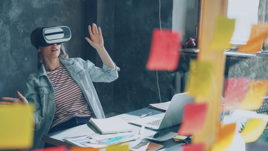 Djelatnica koristi VR headset uz brainstorming s ljepljivim papirićima i laptopom